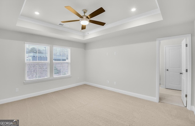 carpeted spare room with ceiling fan and a tray ceiling