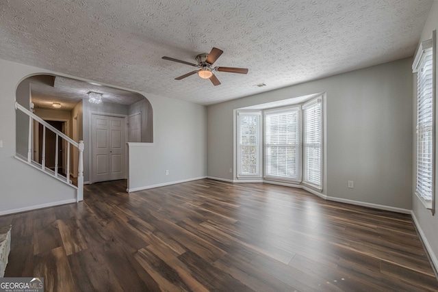 unfurnished living room with a textured ceiling, dark hardwood / wood-style floors, and ceiling fan