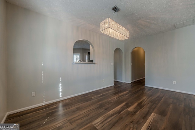 spare room featuring dark hardwood / wood-style flooring, a chandelier, and a textured ceiling