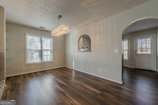 unfurnished dining area featuring a textured ceiling and dark hardwood / wood-style flooring