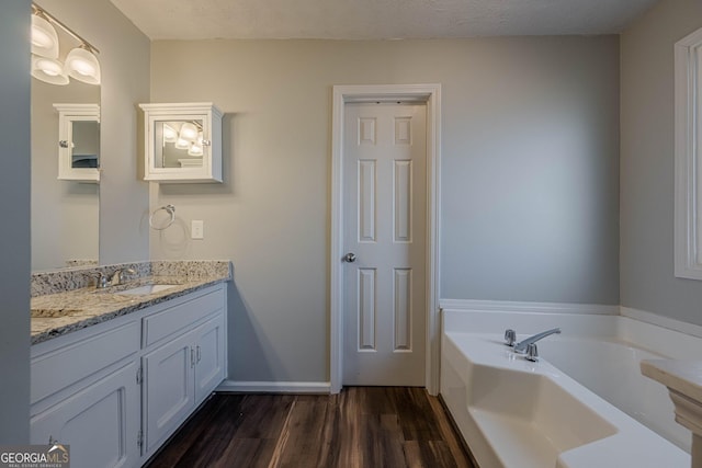 bathroom with vanity, a tub to relax in, wood-type flooring, and a textured ceiling