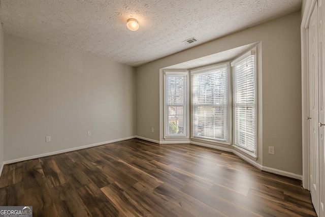 unfurnished room featuring a textured ceiling and dark hardwood / wood-style flooring