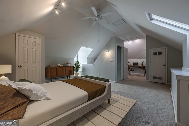 carpeted bedroom with lofted ceiling with skylight, rail lighting, and ceiling fan