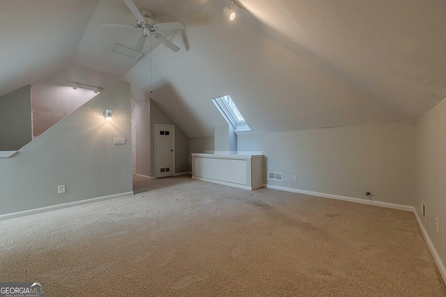 additional living space with light colored carpet, lofted ceiling with skylight, and ceiling fan