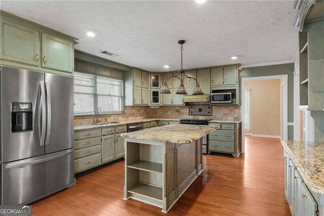 kitchen with sink, decorative light fixtures, green cabinets, a kitchen island, and stainless steel appliances