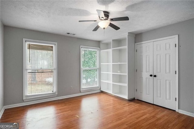 unfurnished bedroom featuring ceiling fan, hardwood / wood-style floors, and a textured ceiling