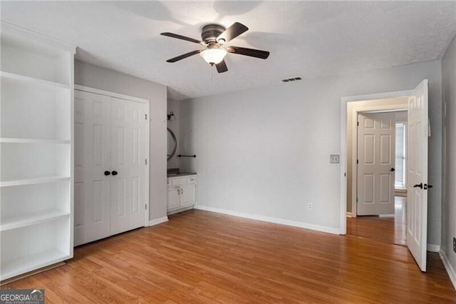 unfurnished bedroom with hardwood / wood-style flooring, a textured ceiling, ceiling fan, and a closet