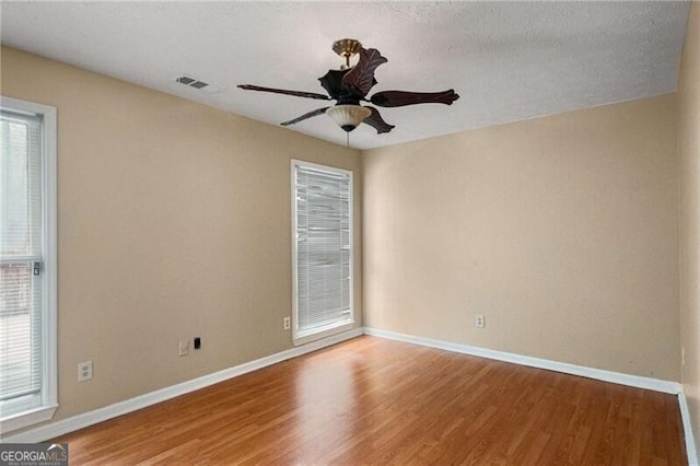 empty room with ceiling fan, hardwood / wood-style floors, and a textured ceiling