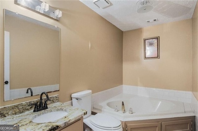 bathroom featuring vanity, a tub, a textured ceiling, and toilet