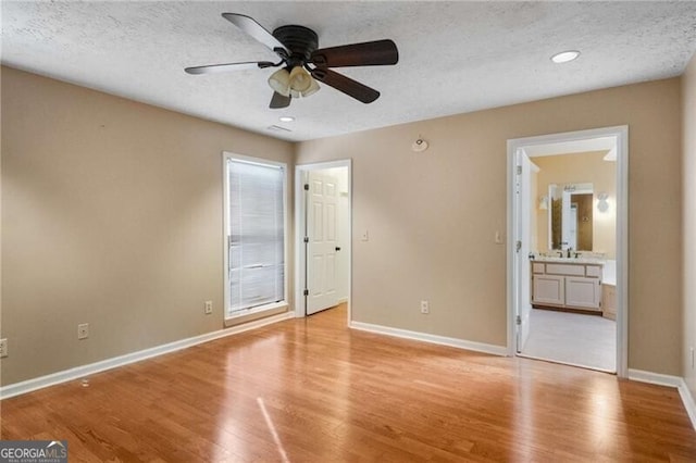 unfurnished bedroom with a textured ceiling, light hardwood / wood-style floors, ceiling fan, and ensuite bathroom