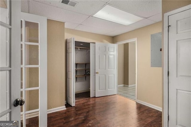 interior space featuring a paneled ceiling, dark hardwood / wood-style floors, and electric panel