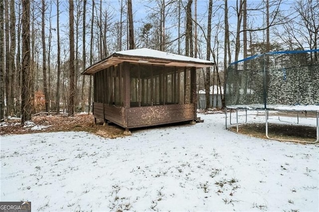 yard layered in snow with a trampoline