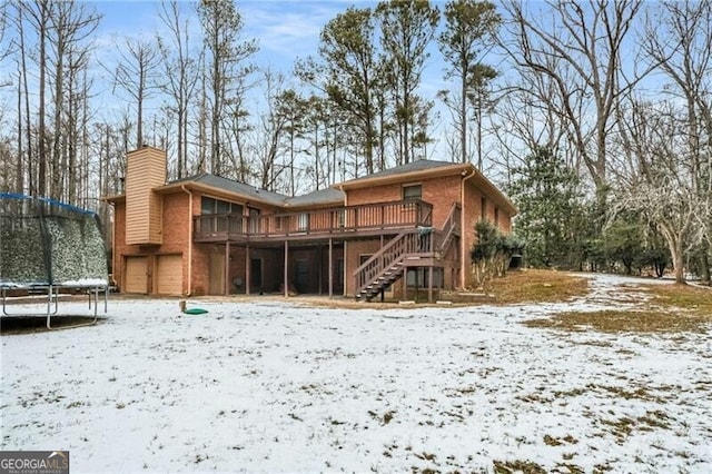 snow covered property featuring a trampoline and a wooden deck