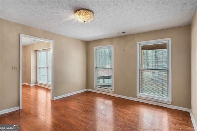 empty room with wood-type flooring and a textured ceiling