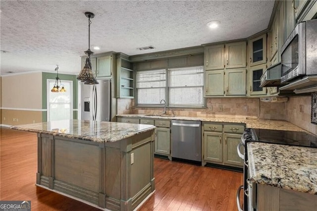 kitchen featuring hanging light fixtures, sink, stainless steel appliances, and a center island