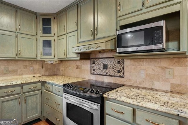 kitchen featuring light stone counters, appliances with stainless steel finishes, and tasteful backsplash