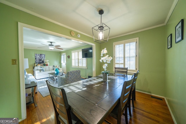 dining room with crown molding, dark wood-type flooring, and a healthy amount of sunlight