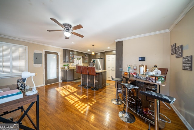 interior space featuring hardwood / wood-style floors, crown molding, bar, and ceiling fan