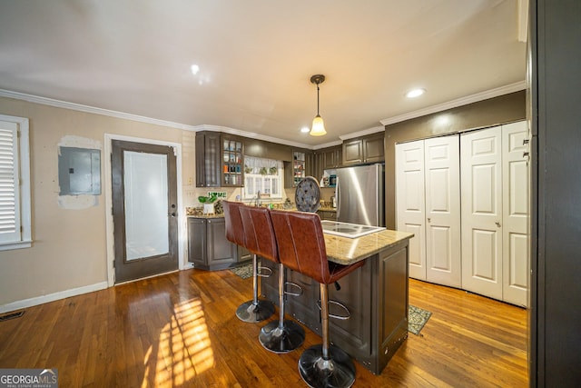 kitchen featuring stainless steel refrigerator, a kitchen island with sink, hanging light fixtures, dark brown cabinets, and electric panel