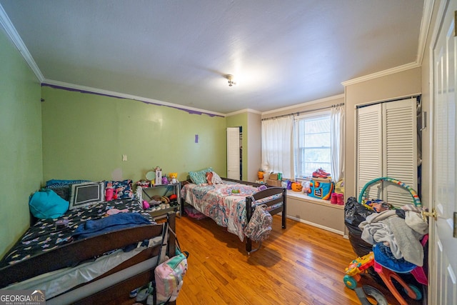 bedroom with crown molding, a closet, and light hardwood / wood-style flooring