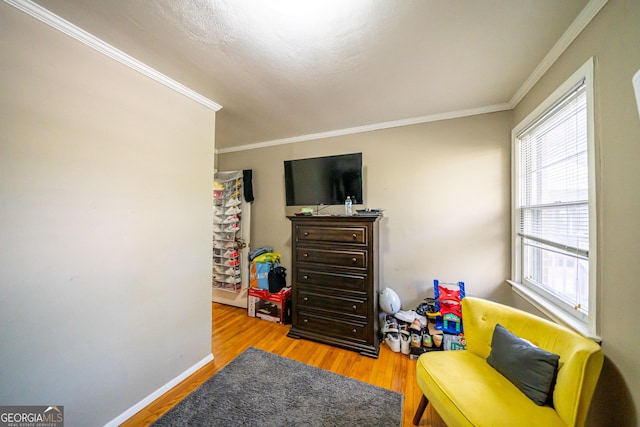 living area with crown molding and light hardwood / wood-style flooring