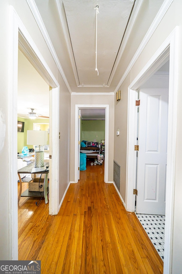 hall with wood-type flooring and ornamental molding