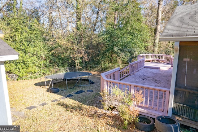 view of yard with a wooden deck and a trampoline