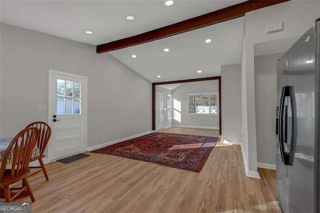 foyer featuring plenty of natural light, light hardwood / wood-style floors, and vaulted ceiling with beams