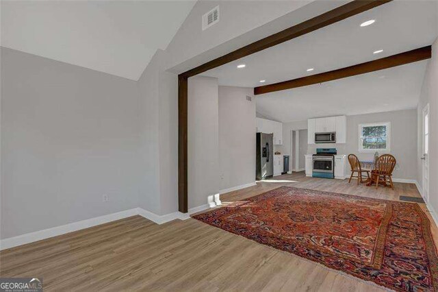 unfurnished living room with lofted ceiling with beams and light hardwood / wood-style floors