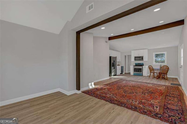 unfurnished living room with vaulted ceiling with beams and light hardwood / wood-style floors