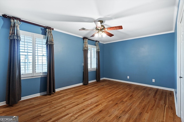 spare room featuring baseboards, wood finished floors, and crown molding