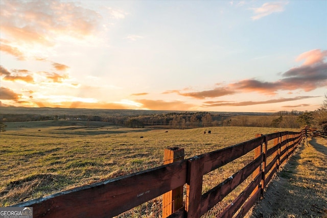 yard at dusk with a rural view and fence