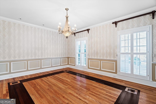 unfurnished dining area with wood finished floors, a wainscoted wall, visible vents, and wallpapered walls