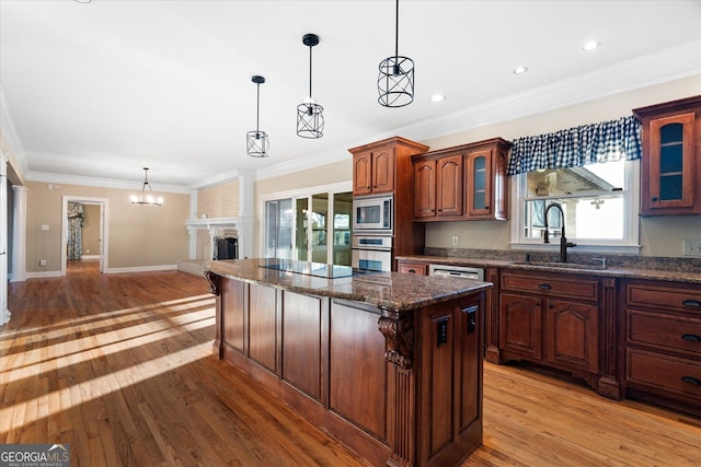 kitchen with pendant lighting, stainless steel appliances, glass insert cabinets, a sink, and a kitchen island