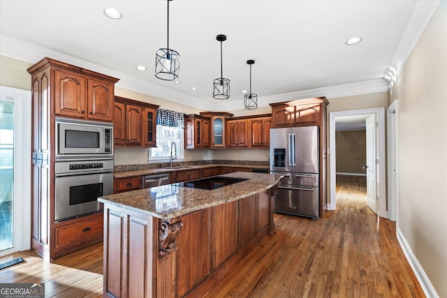 kitchen featuring dark stone counters, a kitchen island, glass insert cabinets, stainless steel appliances, and pendant lighting