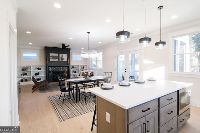 kitchen with pendant lighting, a breakfast bar area, stainless steel microwave, and light hardwood / wood-style flooring