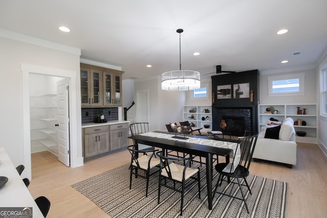 dining space with light hardwood / wood-style flooring, ornamental molding, and a large fireplace