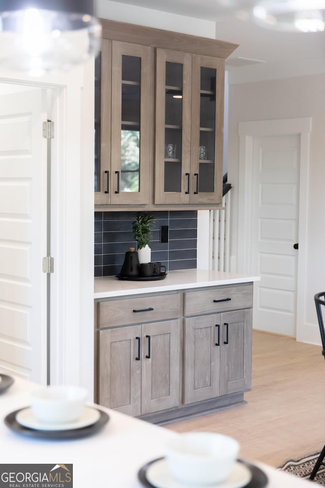 bar featuring backsplash and light hardwood / wood-style flooring