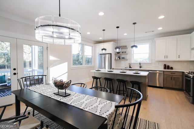 dining room featuring french doors, ornamental molding, a chandelier, and light hardwood / wood-style floors