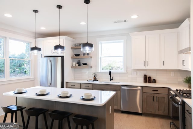 kitchen with stainless steel appliances, a breakfast bar, sink, and white cabinets