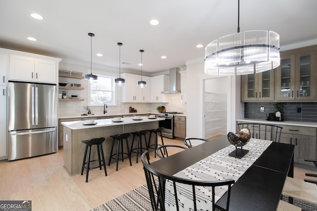 kitchen with white cabinets, stainless steel appliances, a center island, and wall chimney exhaust hood