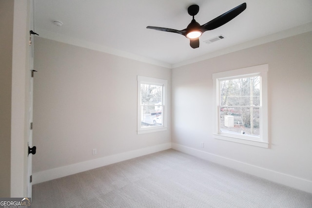 empty room with crown molding, ceiling fan, and carpet