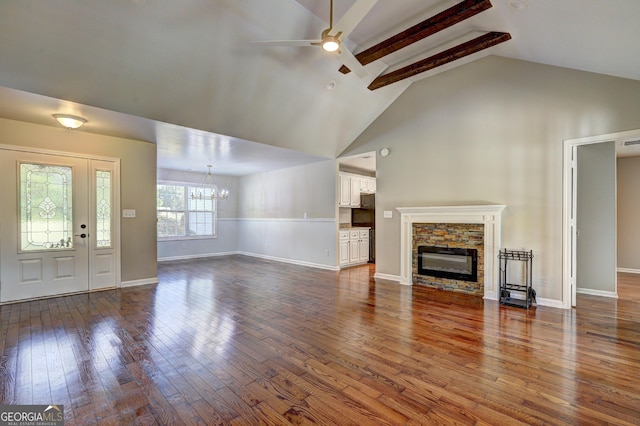 unfurnished living room with beam ceiling, wood-type flooring, and a stone fireplace