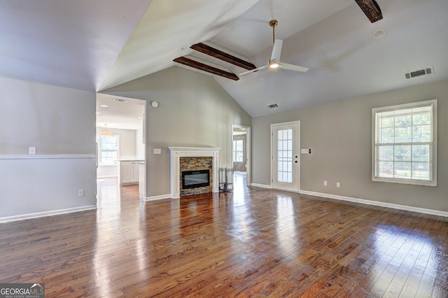 unfurnished living room with visible vents, a stone fireplace, and hardwood / wood-style floors