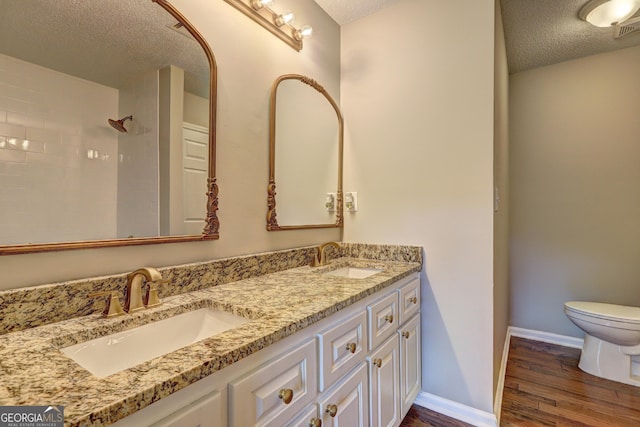 bathroom featuring wood-type flooring, toilet, a textured ceiling, and vanity