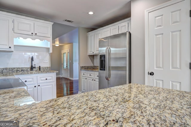 kitchen with white cabinetry, light stone countertops, and stainless steel refrigerator with ice dispenser