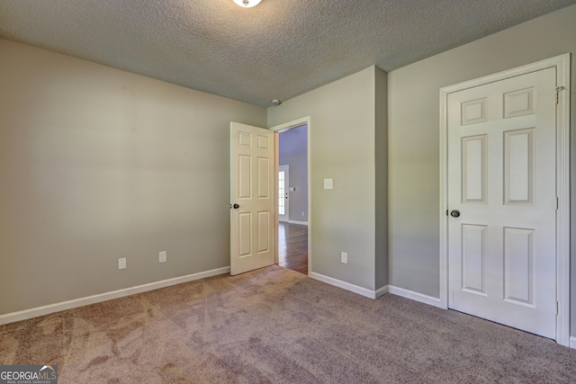 unfurnished bedroom with light colored carpet and a textured ceiling