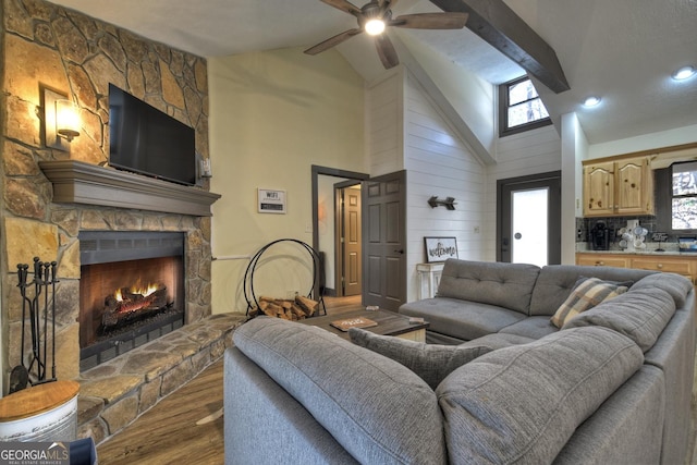 living room featuring a fireplace, wood-type flooring, high vaulted ceiling, and beamed ceiling