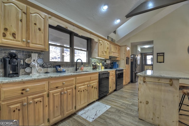 kitchen featuring a kitchen bar, vaulted ceiling, light hardwood / wood-style flooring, appliances with stainless steel finishes, and light stone countertops