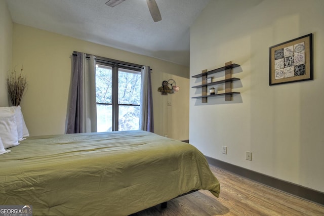 bedroom with ceiling fan, wood-type flooring, and a textured ceiling